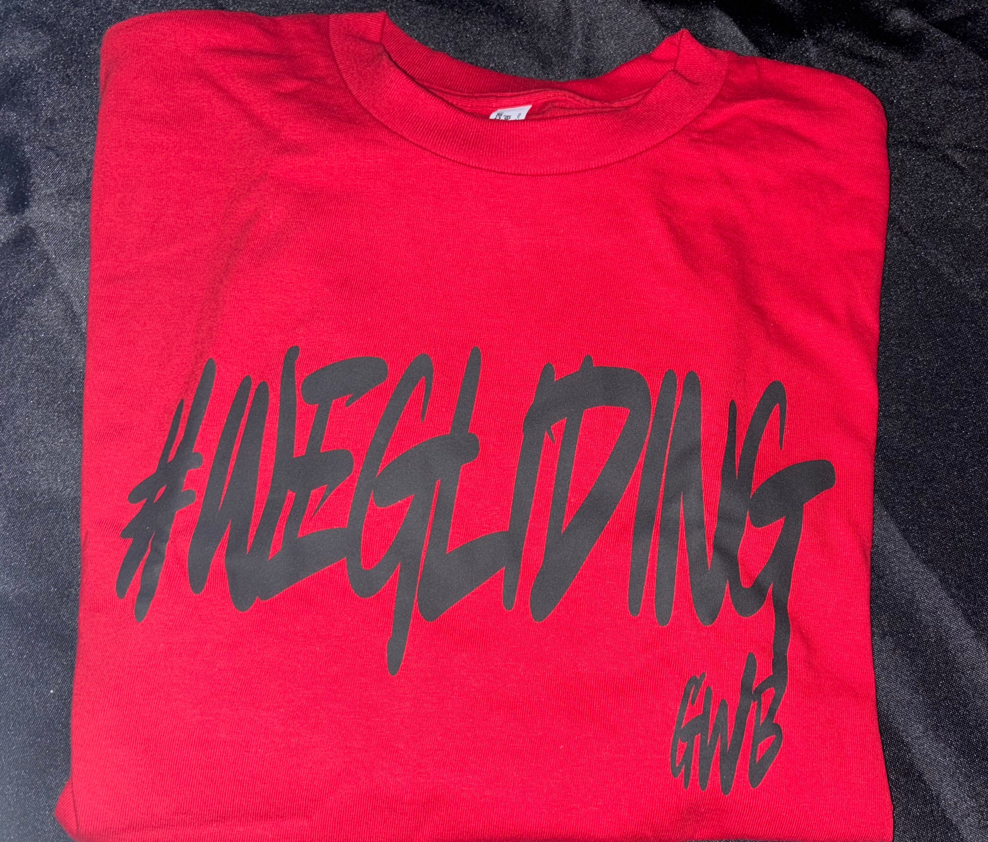 Folded red t-shirt with black text on a dark textured background